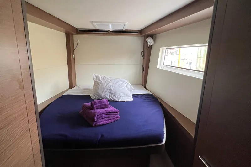 Buena Vida Yacht Photos Pics Luxurious cabin interior of 2023 Lagoon 50 yacht with cozy bed and window view.