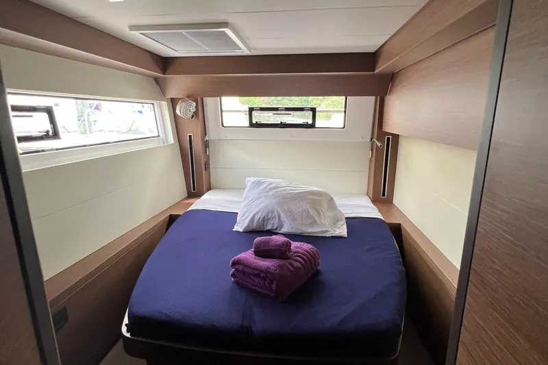 Buena Vida Yacht Photos Pics Luxurious cabin interior of 2023 Lagoon 50 yacht with cozy bed and windows.