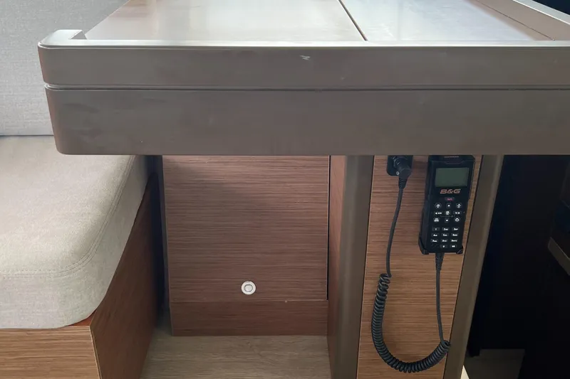 Buena Vida Yacht Photos Pics 2023 Lagoon 50 interior with table, cushioned seating, and mounted communication device.
