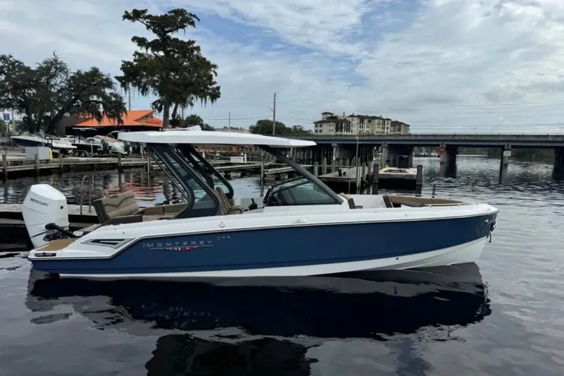  Yacht Photos Pics 2025 Monterey Elite 27 OB boat docked on a calm waterfront with scenic background.