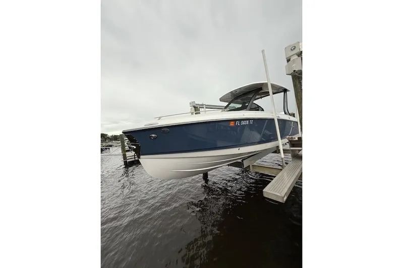  Yacht Photos Pics 2025 Monterey Elite 27 OB boat docked on water, showcasing sleek blue and white design.