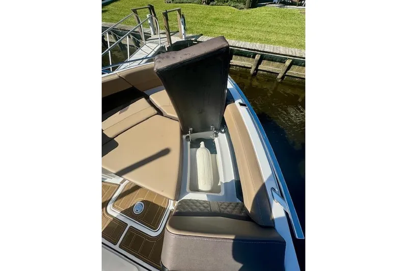  Yacht Photos Pics 2025 Monterey Elite 27 OB boat with open storage compartment, docked by grassy area.