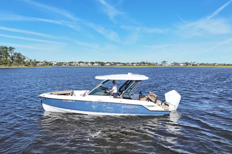  Yacht Photos Pics 2025 Monterey Elite 27 OB boat cruising on a calm lake under a clear blue sky.