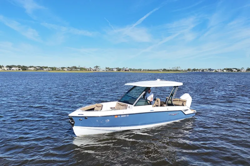  Yacht Photos Pics 2025 Monterey Elite 27 OB boat cruising on a calm lake under a clear blue sky.