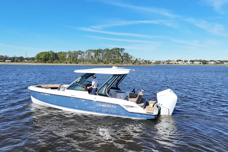 Yacht Photos Pics 2025 Monterey Elite 27 OB boat cruising on a calm lake under a clear blue sky.