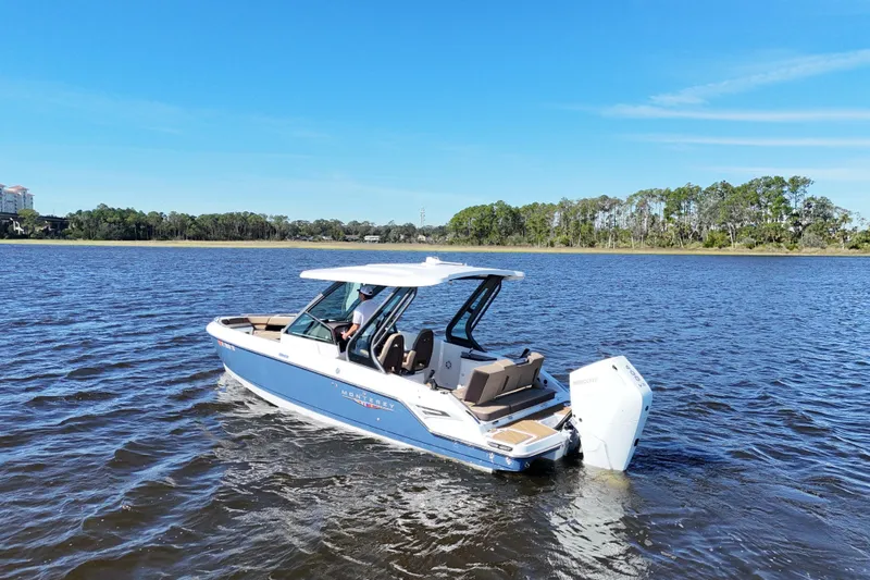  Yacht Photos Pics 2025 Monterey Elite 27 OB boat cruising on a serene lake under a clear blue sky.