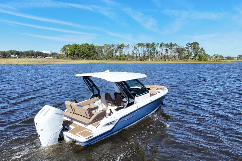  Yacht Photos Pics 2025 Monterey Elite 27 OB boat cruising on a serene lake under a clear blue sky.