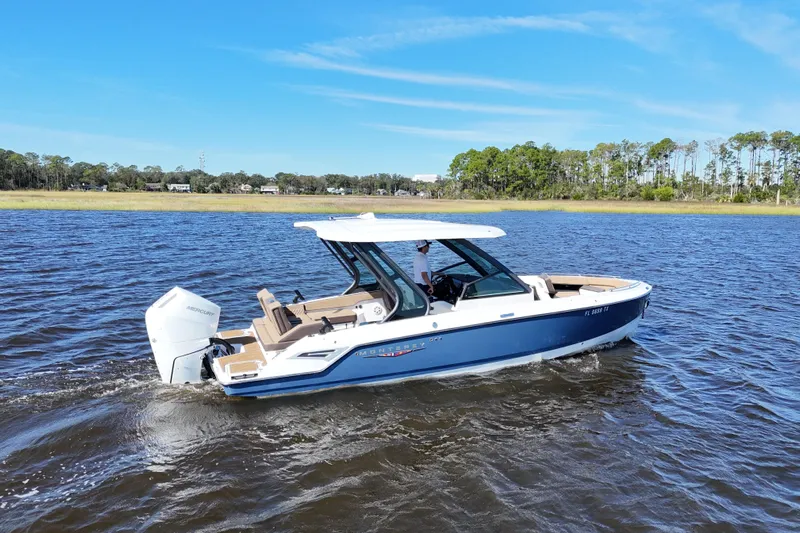  Yacht Photos Pics 2025 Monterey Elite 27 OB boat cruising on a sunny day in a scenic waterway.