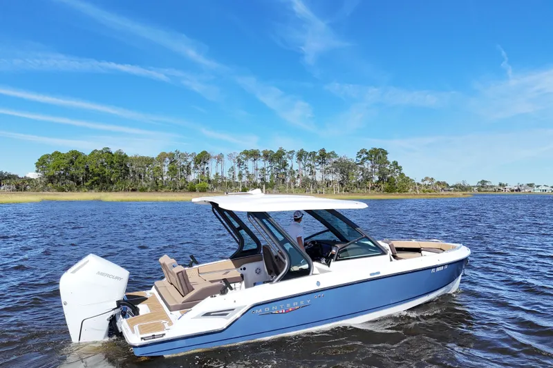  Yacht Photos Pics 2025 Monterey Elite 27 OB boat cruising on a scenic lake under a clear blue sky.