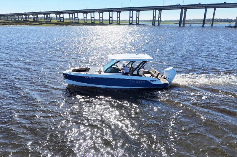  Yacht Photos Pics 2025 Monterey Elite 27 OB boat cruising on a sunny day near a bridge.