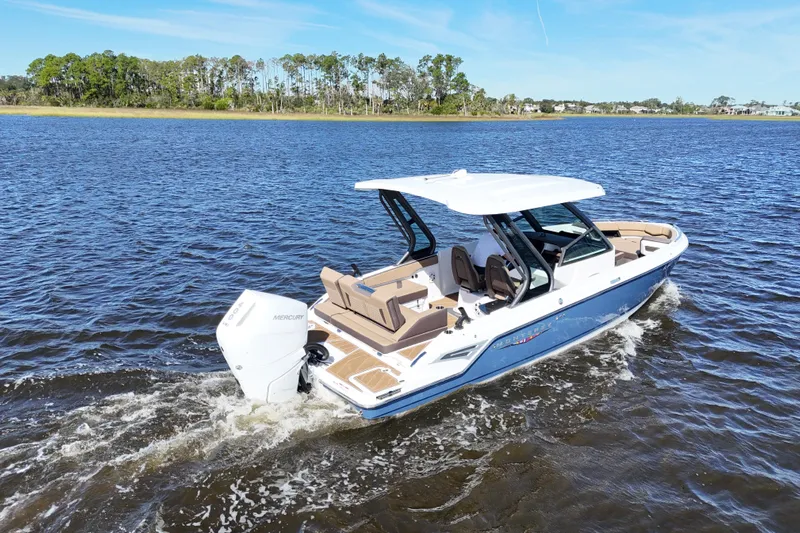 Yacht Photos Pics 2025 Monterey Elite 27 OB boat cruising on a serene lake under a clear blue sky.