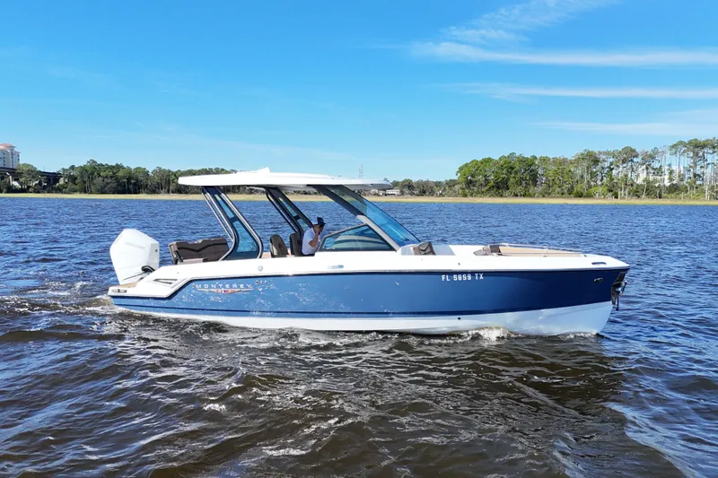  Yacht Photos Pics 2025 Monterey Elite 27 OB boat cruising on a scenic lake under a clear blue sky.