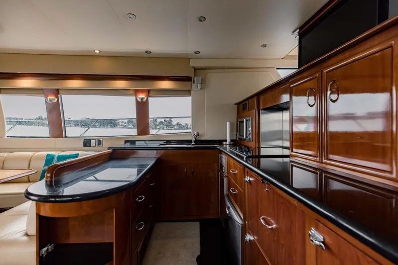 Sonshine Yacht Photos Pics Luxurious kitchen interior of 2004 Carver 56 Voyager yacht with wood cabinetry and black countertops.