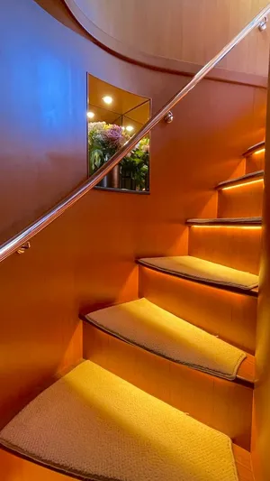 Perseus Yacht Photos Pics Curved wooden staircase with soft lighting in a 2004 Fleming 75 yacht interior.