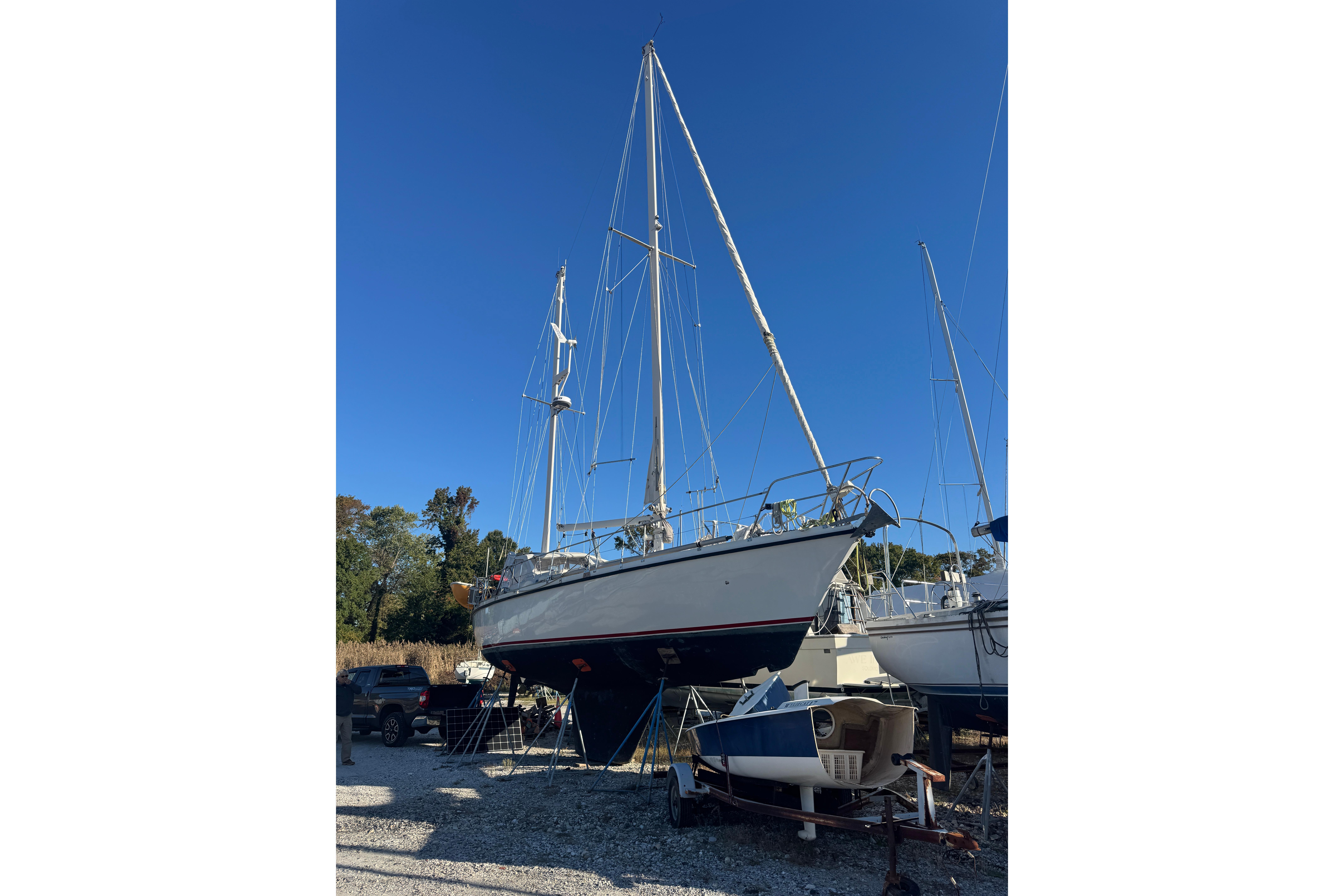 Sailboat Amel Sharki 1988 on land, clear blue sky background.