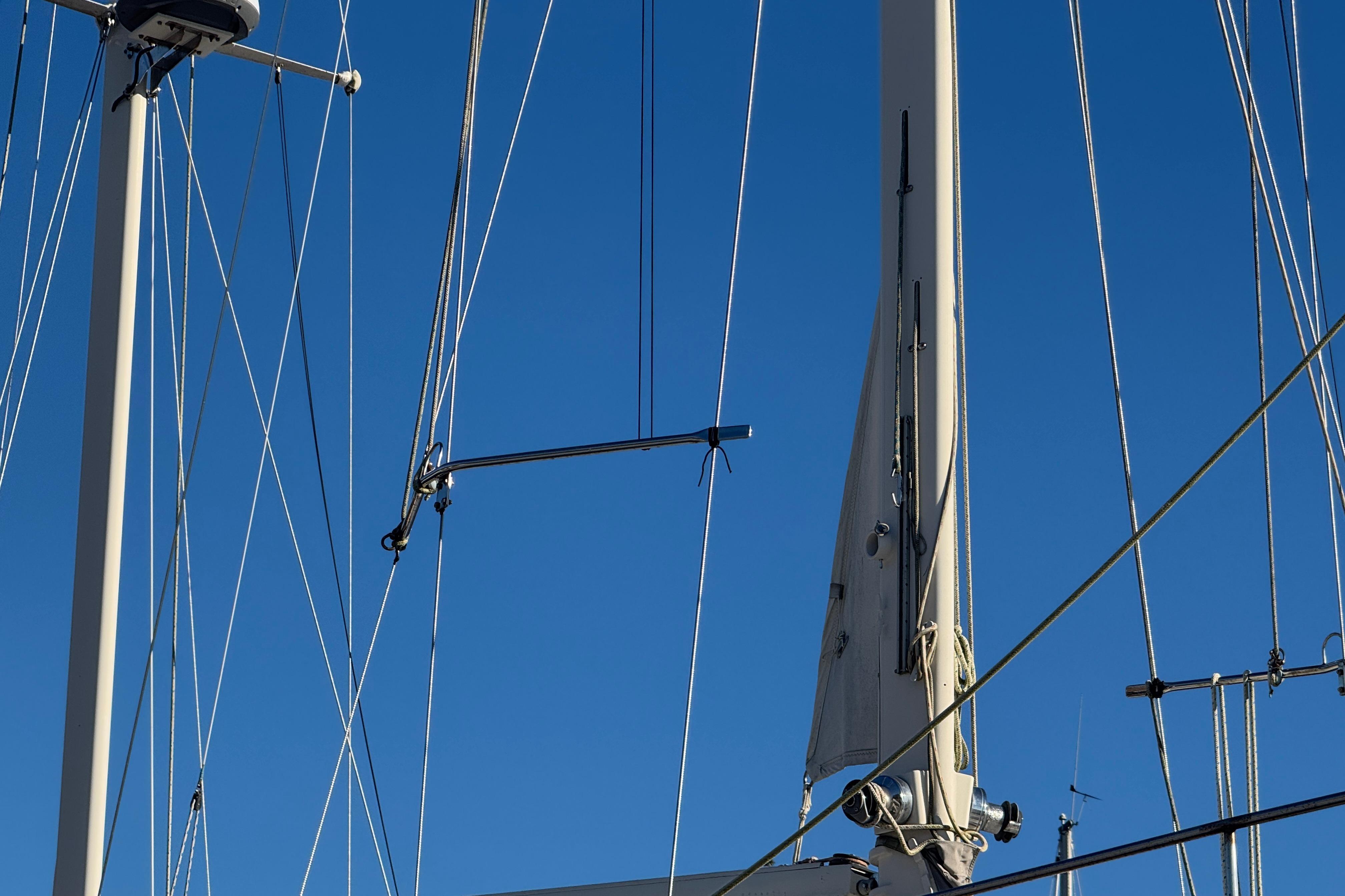 Mast and rigging of 1988 Amel Sharki sailboat against clear blue sky.