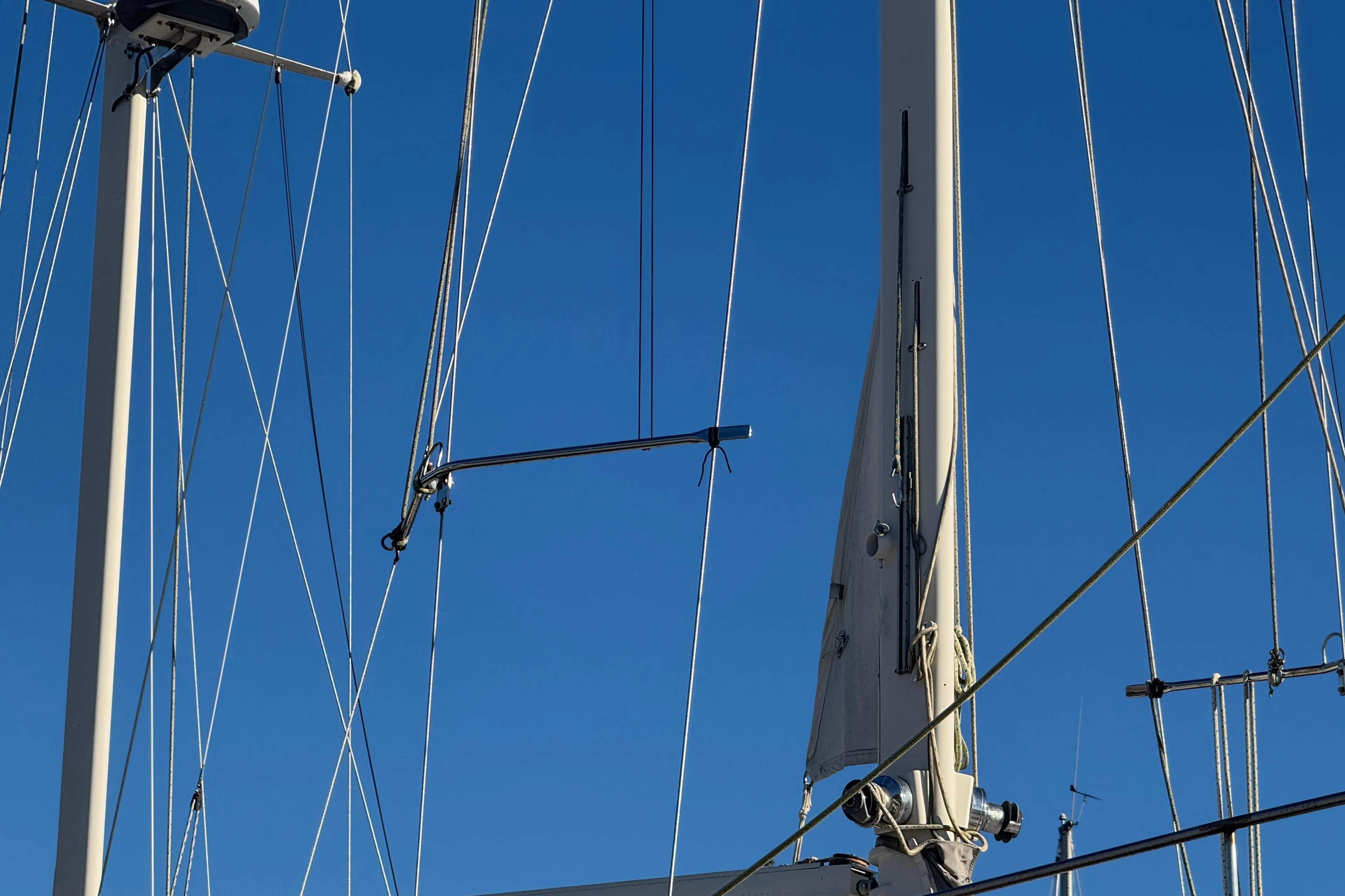 Mast and rigging of 1988 Amel Sharki sailboat against clear blue sky.
