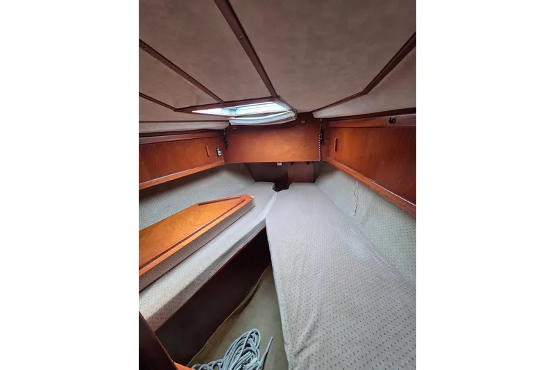Fiasco Yacht Photos Pics Interior cabin of 1988 Amel Sharki sailboat with wooden finish and cozy bedding.