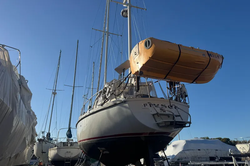 Fiasco Yacht Photos Pics 1988 Amel Sharki sailboat in dry dock with lifeboat, clear blue sky background.
