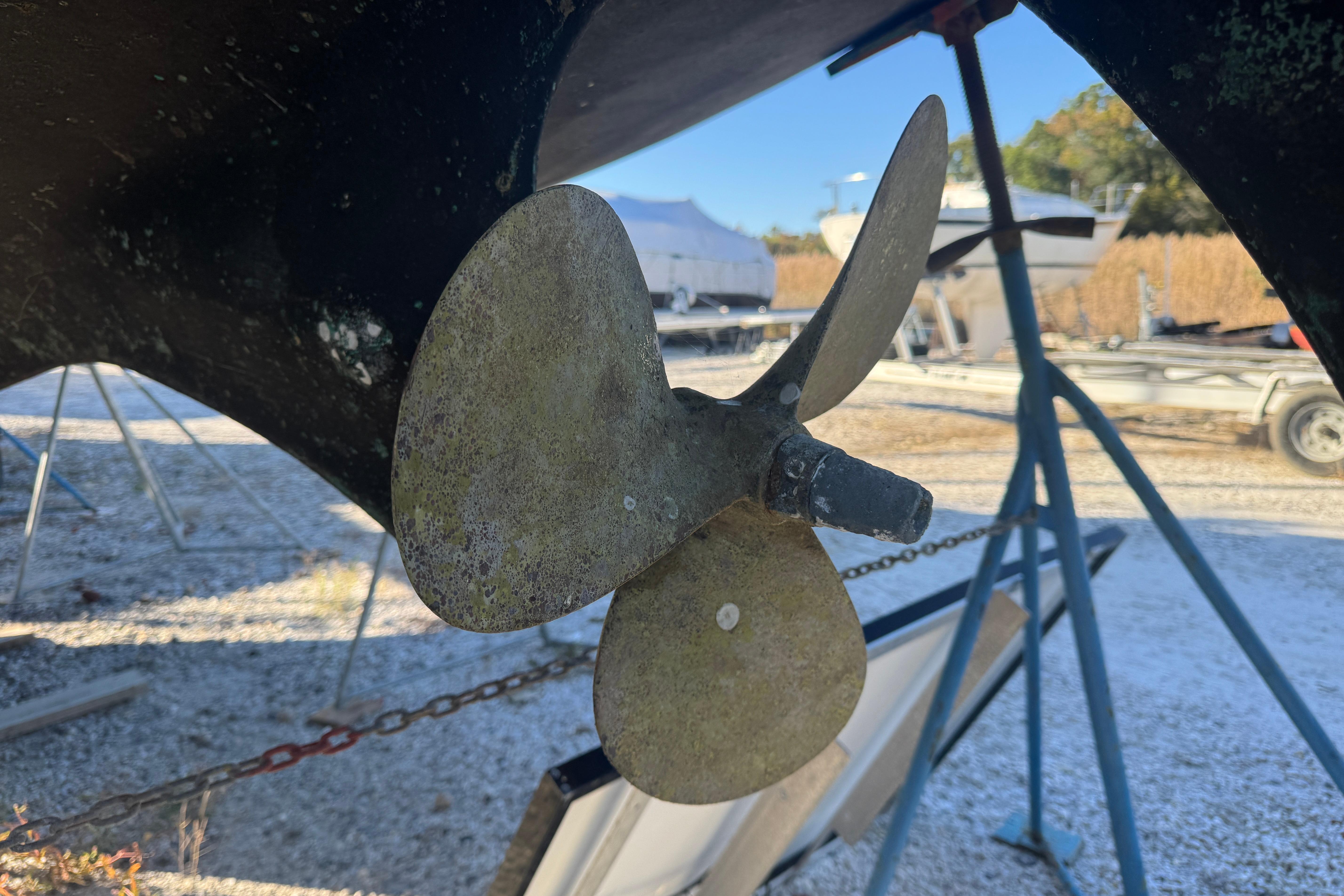 Close-up of a 1988 Amel Sharki boat propeller on a stand outdoors.