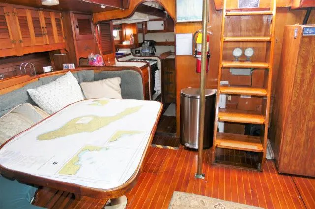 Spirit Yacht Photos Pics Interior of 1979 Roberts 54 sailboat with dining area, kitchen, and wooden stairs.