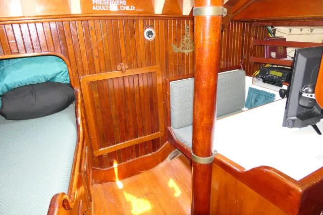 Spirit Yacht Photos Pics 1979 Roberts 54 boat interior with wooden paneling, bed, and navigation desk.
