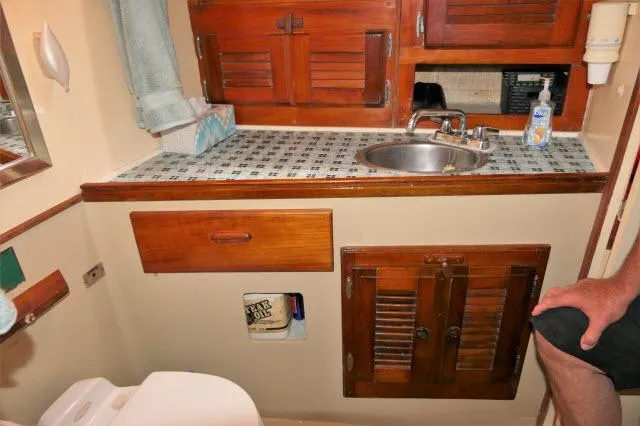 Spirit Yacht Photos Pics 1979 Roberts 54 boat bathroom with wooden cabinets, sink, and tiled countertop.