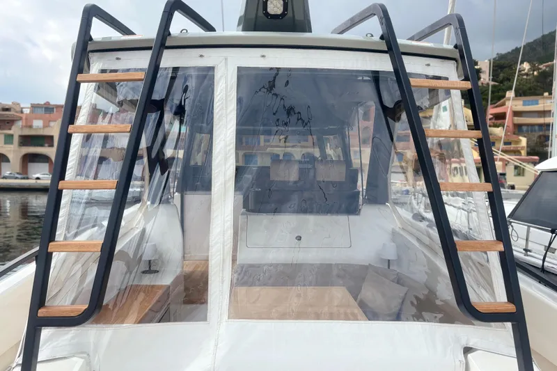  Yacht Photos Pics 2021 Bluegame BG42 yacht with clear enclosure and wooden ladder details in a marina setting.