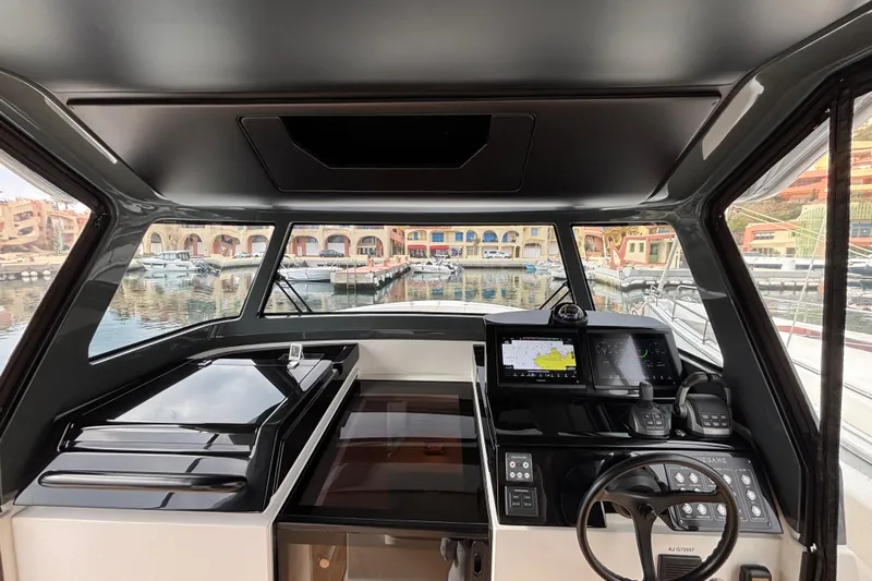  Yacht Photos Pics Interior view of 2021 Bluegame BG42 yacht cockpit with navigation equipment and marina backdrop.