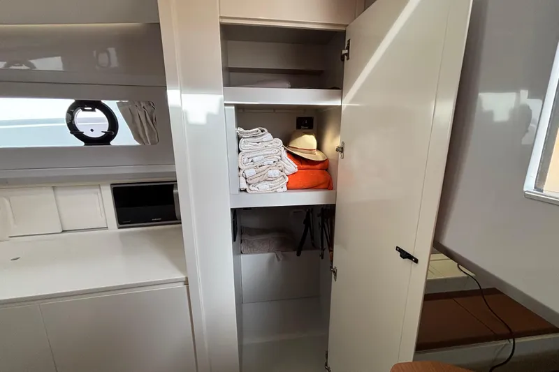 Yacht Photos Pics 2021 Bluegame BG42 yacht interior with open storage cabinet, towels, and hat.