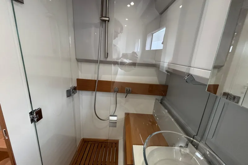  Yacht Photos Pics Modern shower area in 2021 Bluegame BG42 yacht, featuring glass doors and wooden accents.
