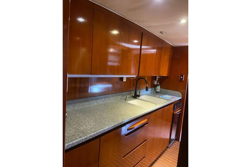 New Beginning Yacht Photos Pics Luxurious kitchen interior of 1990 Cheoy Lee 75 yacht with wooden cabinets and modern sink.