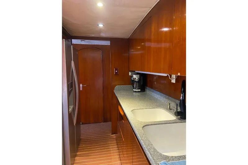 New Beginning Yacht Photos Pics Galley kitchen in 1990 Cheoy Lee 75 yacht with wood cabinetry and modern appliances.