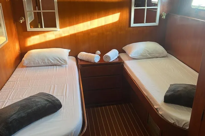 New Beginning Yacht Photos Pics Twin cabin with wooden interior on 1990 Cheoy Lee 75 yacht, featuring cozy beds and soft lighting.