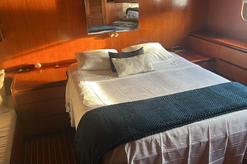 New Beginning Yacht Photos Pics Luxurious bedroom interior on 1990 Cheoy Lee 75 yacht with elegant wood paneling.