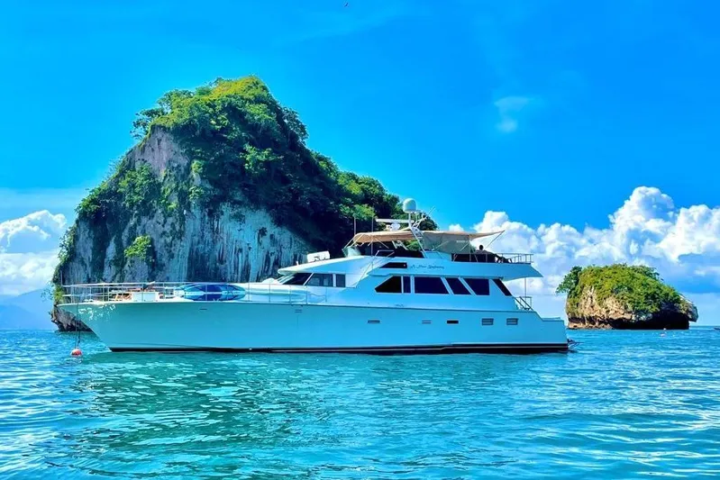 New Beginning Yacht Photos Pics Luxurious 1990 Cheoy Lee 75 yacht cruising near lush tropical islands under a clear blue sky.