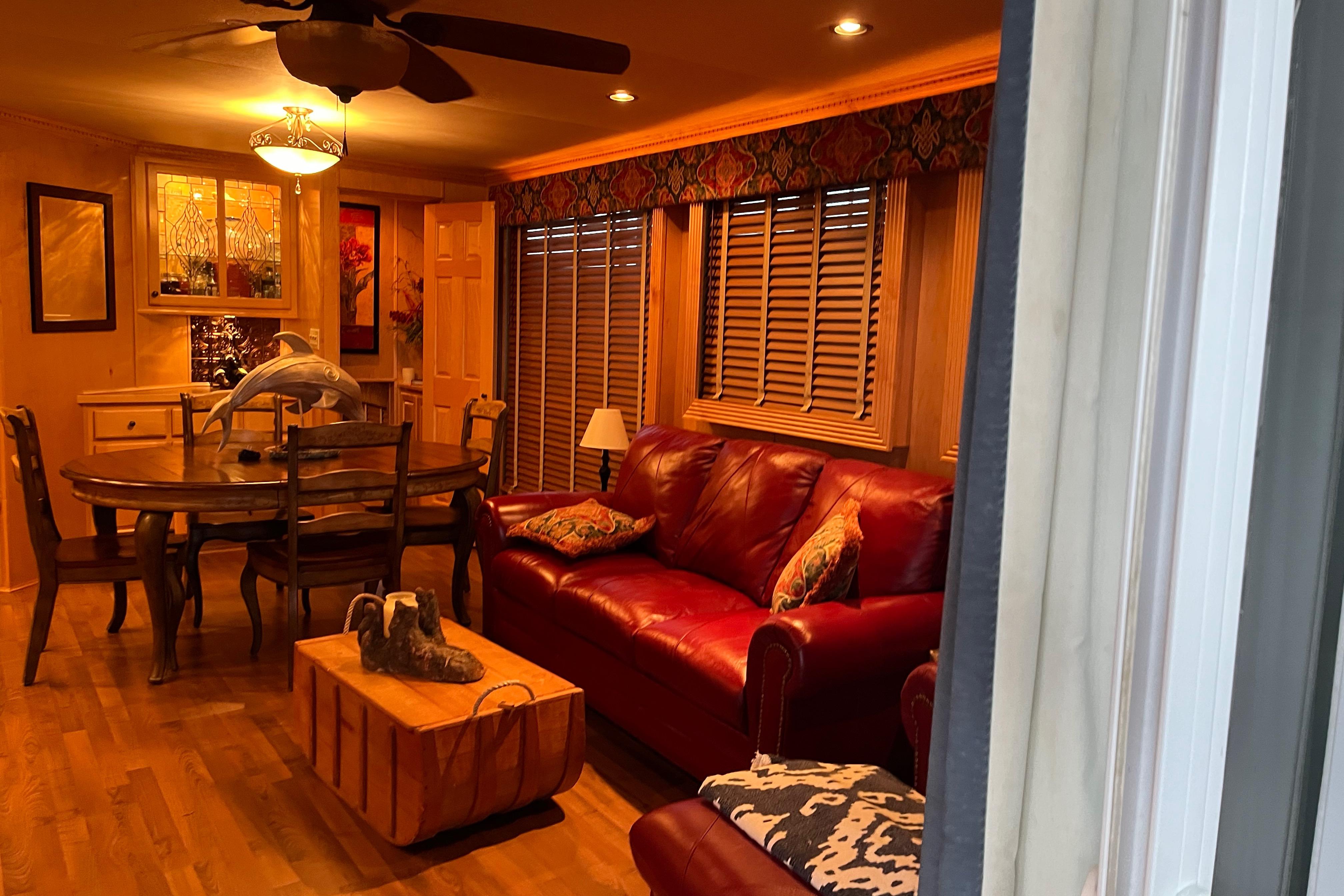 Cozy living room with red leather sofa, dining table, and warm lighting. Funtime 68x16, 2010 model.