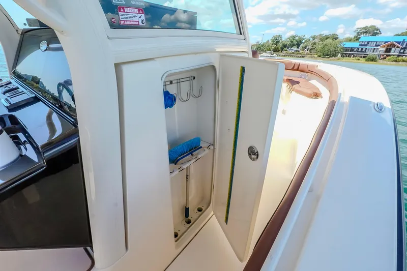  Yacht Photos Pics 2017 Scout 300 LXF boat storage compartment with cleaning tools, docked by the water.