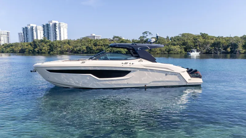  Yacht Photos Pics 2021 Cruisers Yachts 38 GLS OB 450R on calm water, with cityscape and trees in background.