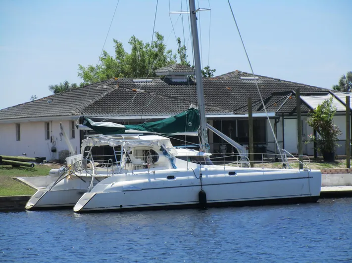 Felice Yacht Photos Pics 1998 Fountaine Pajot Athena 38 catamaran docked by a waterfront house.
