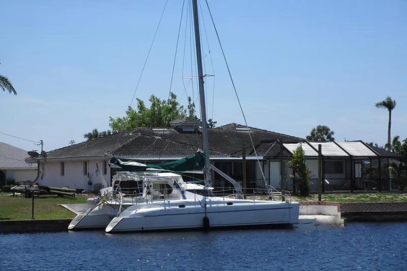 Felice Yacht Photos Pics 1998 Fountaine Pajot Athena 38 catamaran docked by a waterfront house.