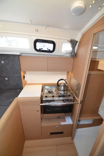 Sea To Summit Yacht Photos Pics Modern kitchen in 2022 Jeanneau Sun Odyssey 349 sailboat, featuring compact stove and cabinetry.