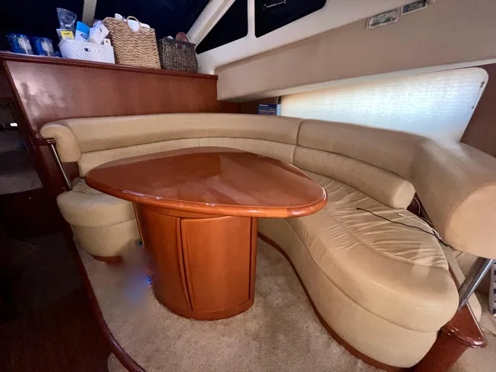 Knot On Call II Yacht Photos Pics Luxurious interior of 2006 Silverton 43 Sport Bridge yacht with curved seating and wooden table.