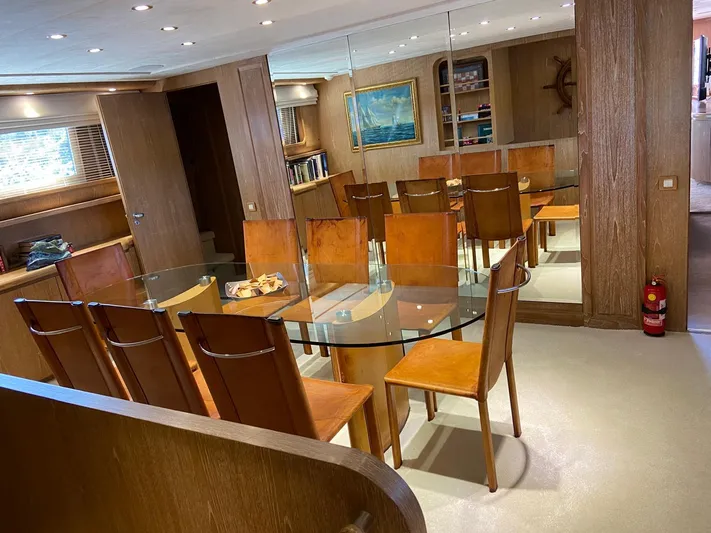  Yacht Photos Pics Luxurious dining area on 1992 Cantieri di Pisa Akhir 30S yacht with glass table and wooden chairs.