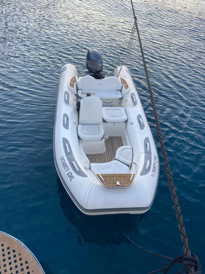  Yacht Photos Pics Inflatable boat moored on water, featuring seating and an outboard motor.