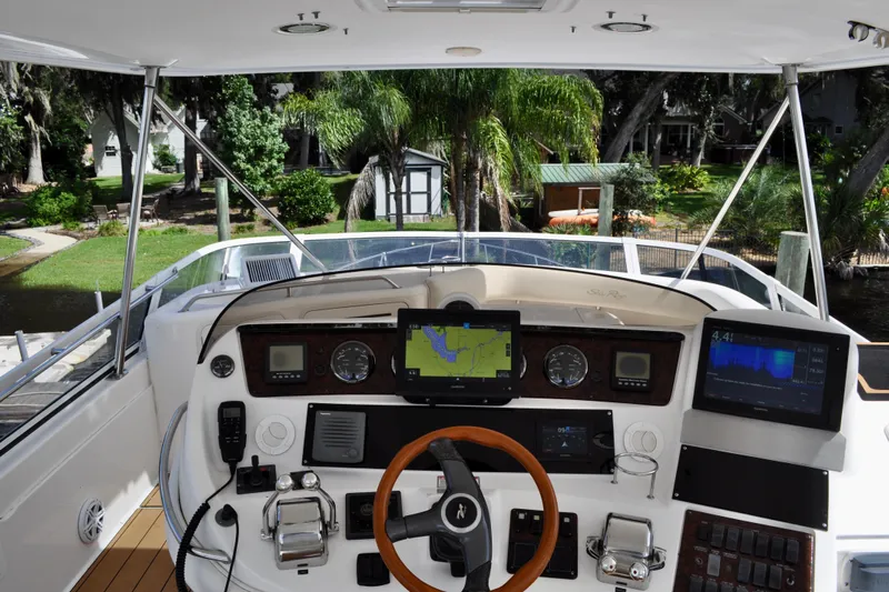 King Leisure Yacht Photos Pics 2002 Sea Ray 480 Sedan Bridge helm with navigation screens and controls, docked near lush greenery.