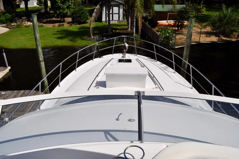 King Leisure Yacht Photos Pics 2002 Sea Ray 480 Sedan Bridge yacht docked, view from the bow, surrounded by greenery.