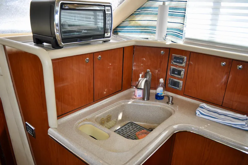 King Leisure Yacht Photos Pics 2002 Sea Ray 480 Sedan Bridge kitchen with sink, toaster oven, and wooden cabinets.