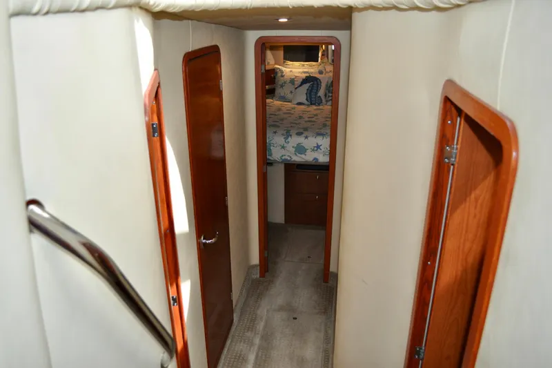 King Leisure Yacht Photos Pics Interior hallway of 2002 Sea Ray 480 Sedan Bridge yacht, featuring wooden doors and cozy bedroom.