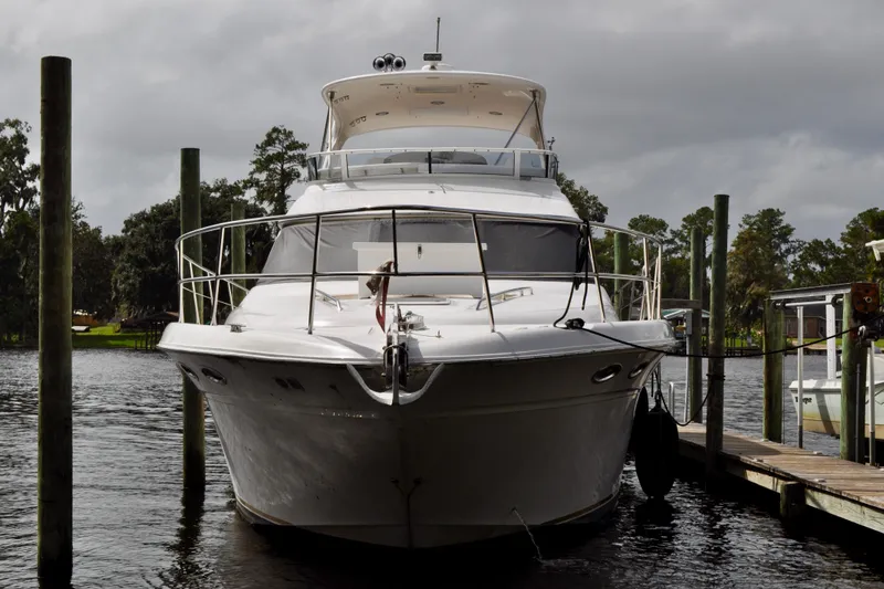 King Leisure Yacht Photos Pics 2002 Sea Ray 480 Sedan Bridge yacht docked on a calm river under cloudy skies.